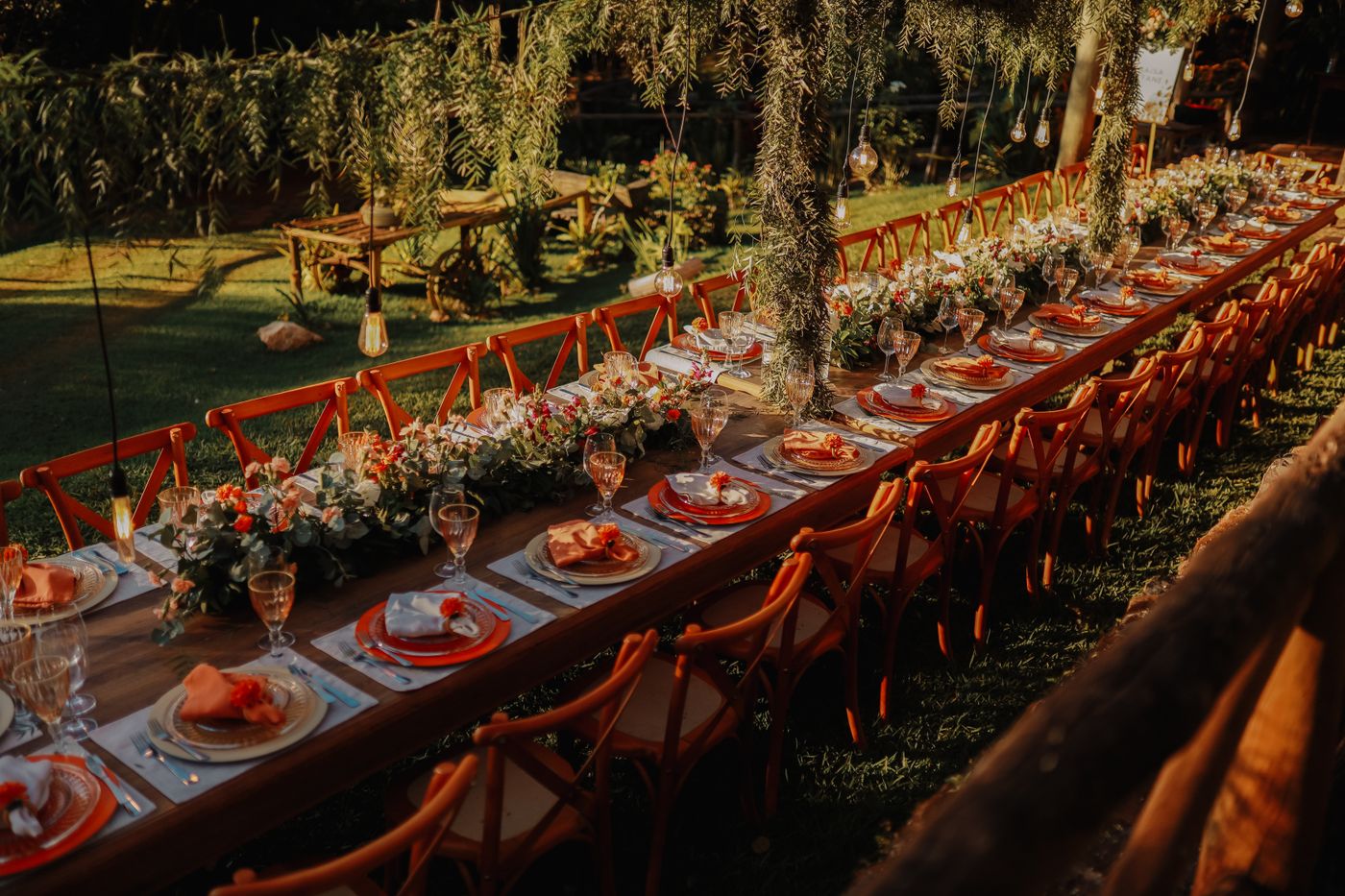 A very long banquet table dressed with flowers and garlands in the evening light
