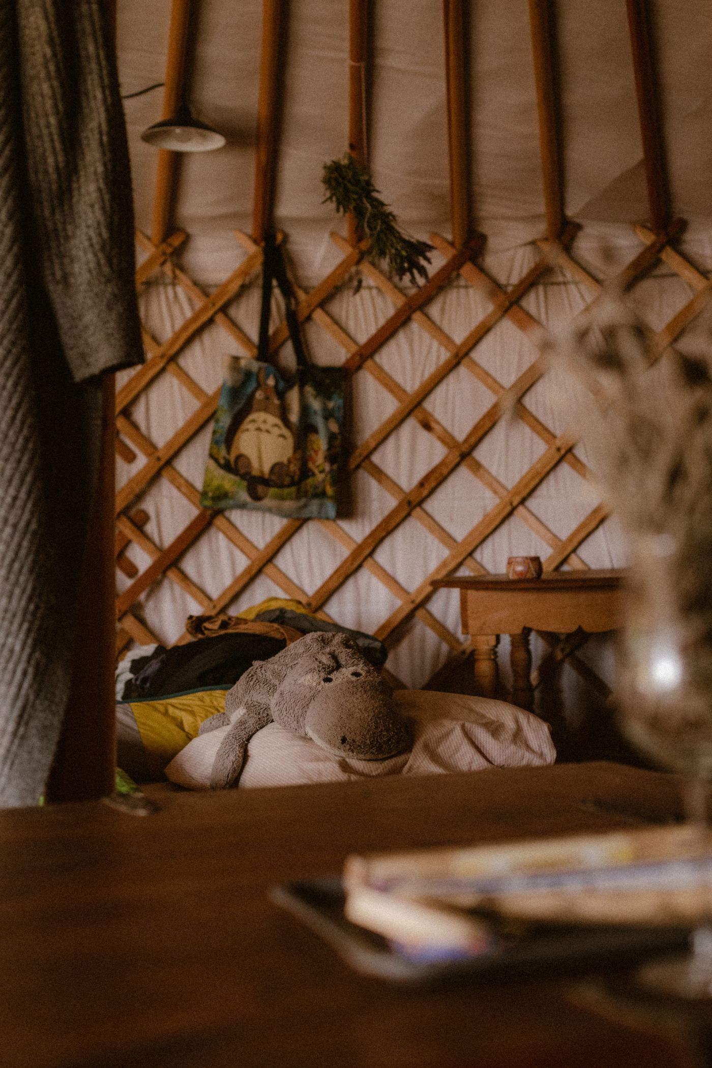 The warm timber-lattice interior of a yurt with a bed and a small table
